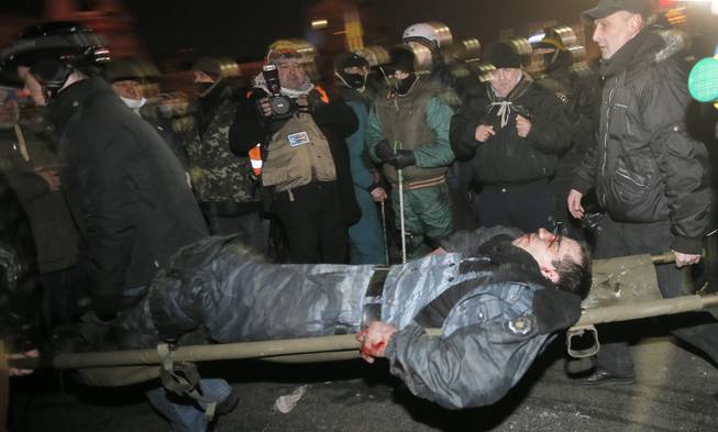 Anti-government protesters carry a wounded policemen during clashes with riot police in Kiev's Independence Square, the epicenter of the country's current unrest,  Kiev, Ukraine, Wednesday, Feb. 19, 2014. Thousands of angry anti-government protesters clashed with police in a new eruption of violence following new maneuvering by Russia and the European Union to gain influence over this former Soviet republic. 