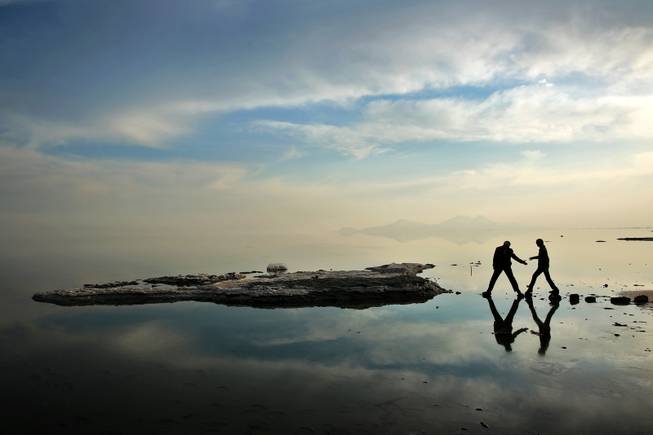In this Saturday, Feb. 15, 2014 photo,  two men walk toward salt-covered rocks that were once deep underwater at Lake Oroumieh, in northwestern Iran.