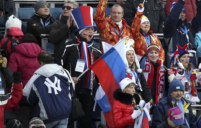 Fans waving a Russian flag cheer during the women's biathlon at the 2014 Winter Olympics in Krasnaya Polyana, Russia, Feb. 9, 2014. 