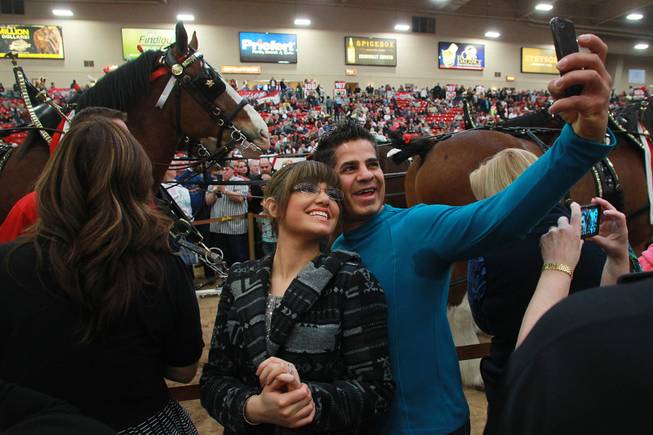 Australians Paria and Michael Sobbi take a photo during an appearance of the Budweiser Clydesdales at the South Point Arena Thursday, Feb. 20, 2014.