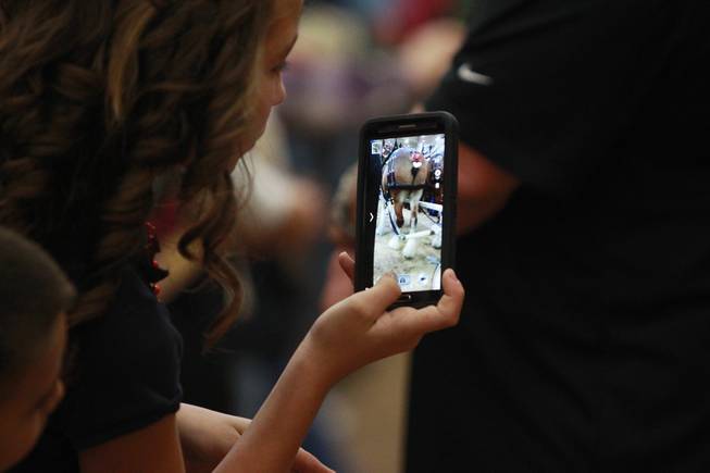 An attendee uses her phono to take a picture during an appearance of the Budweiser Clydesdales at the South Point Arena Thursday, Feb. 20, 2014.