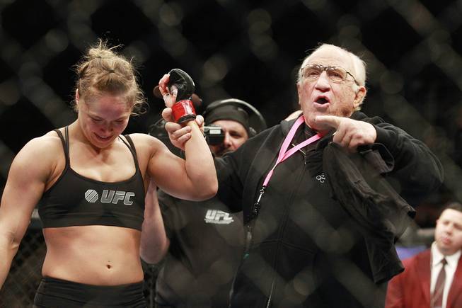 Martial arts legend, coach and friend Gene LaBell raises Ronda Rousey's arm after her first round TKO of Sara McMann in their fight at UFC 170 Saturday, Feb. 22, 2014 at the Mandalay Bay Events Center.