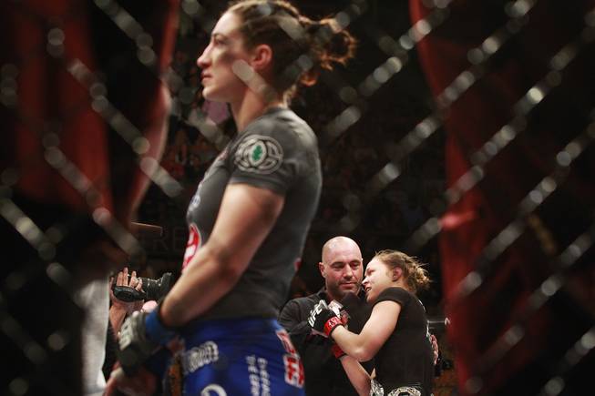 Ronda Rousey talks with Joe Rogan as Sara McMann watches a replay of their fight at UFC 170 Saturday, Feb. 22, 2014 at the Mandalay Bay Events Center. Rousey won by TKO in the first round with a knee to the McMann's liver.