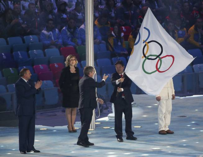 Mayor of Sochi Anatoly Pakhomov, left, and International Olympic Committee President Thomas Bach, second from left, look on as Lee Seok-rai, mayor of Pyeongchang, waves the Olympic flag during the closing ceremony for the 2014 Winter Olympics at Fisht Olympic Stadium in Sochi, Russia, Feb. 23, 2014. (Doug Mills/The New York Times)