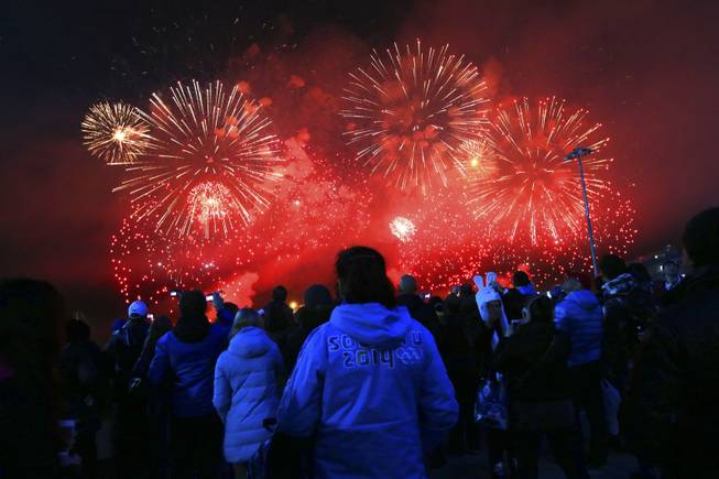 An observer wearing a Sochi 2014 jacket watches fireworks erupt during the closing ceremony for the 2014 Winter Olympics at Fisht Olympic Stadium in Sochi, Russia, Feb. 23, 2014. (Doug Mills/The New York Times)