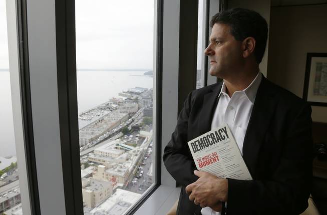 In this Aug. 2, 2013 file photo, venture capitalist Nick Hanauer stands by the window of his office in downtown Seattle. He holds a copy of "Democracy: A Journal of Ideas," which includes an article he co-authored promoting an economy driven by a strong middle class.