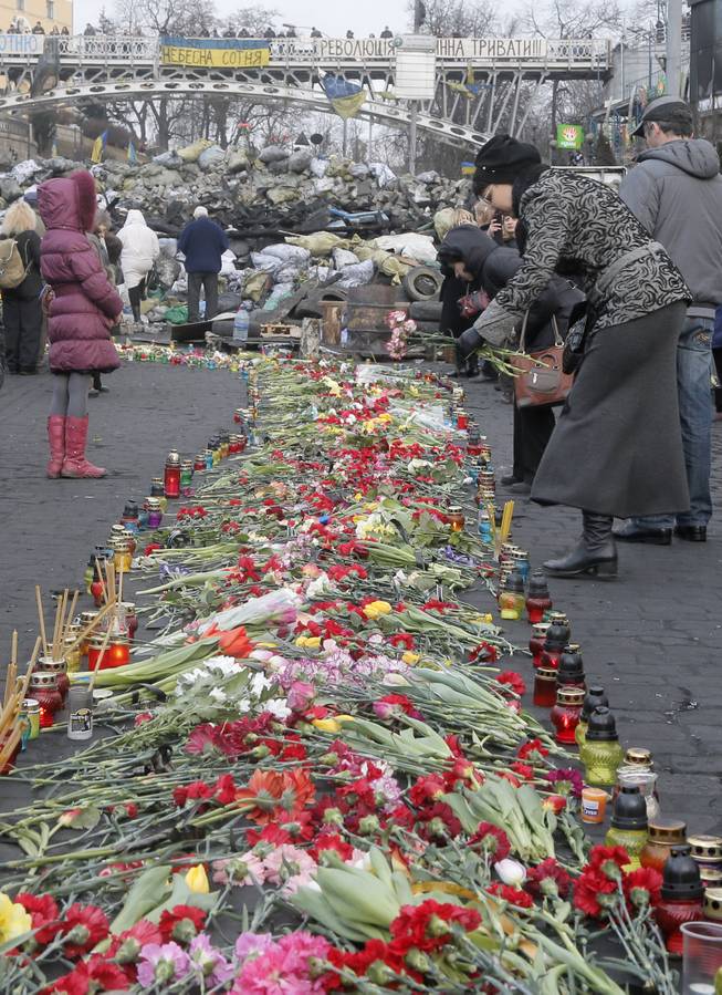 People lays down flowers at one of the streets leading to Independence Square, Kiev, the epicenter of the country's recent unrest, on a mourning day Monday, Feb. 24, 2014. 