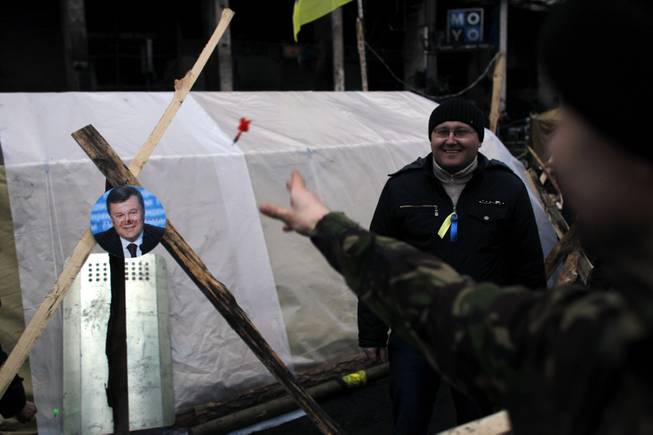 A portrait of Ukraine's President Viktor Yanukovych is used for a game of darts at Independence Square in Kiev, Ukraine, Monday, Feb. 24, 2014. 