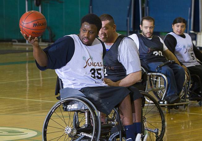 Timothy Oliver keeps the ball away from Marc Fenn during wheelchair basketball practice at Rancho High School Tuesday, Feb. 25, 2014. The team is practicing for a scrimmage against a Wounded Warriors team at Nellis Air Force Base on Thursday.