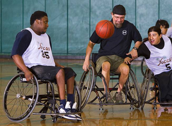 Timothy Oliver, left, Jonathan Foster, center, and Steven Morales go after a loose ball during wheelchair basketball practice at Rancho High School Tuesday, Feb. 25, 2014. Foster works for the City of Las Vegas and helps head the Las Vegas Paralympic Sport Club.