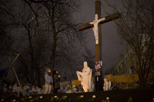 Two woman pray at a memorial for the people killed in clashes with the police at Kiev's Independence Square, the epicenter of the country's current unrest, Ukraine, Tuesday, Feb. 25, 2014. 