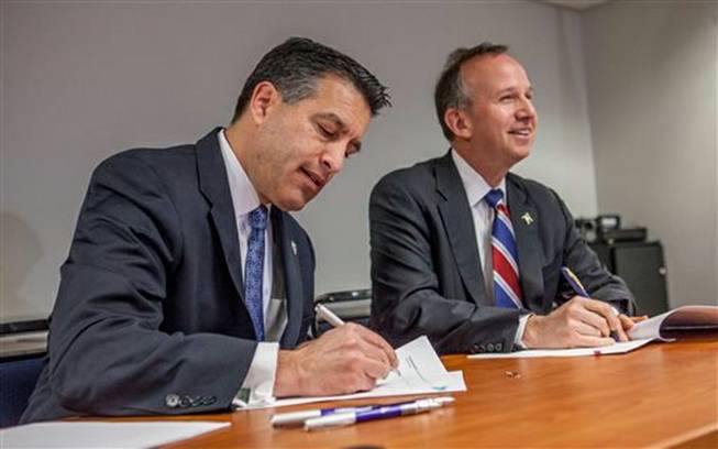 Nevada Gov. Brian Sandoval and Delaware Gov. Jack Markell sign a multistate Internet gaming agreement Tuesday, Feb. 25, 2014, in Wilmington, Del. The agreement establishes a legal framework allowing residents of the two states to play online poker against each other. The agreement also allows other states to join the agreement with the approval of existing members.