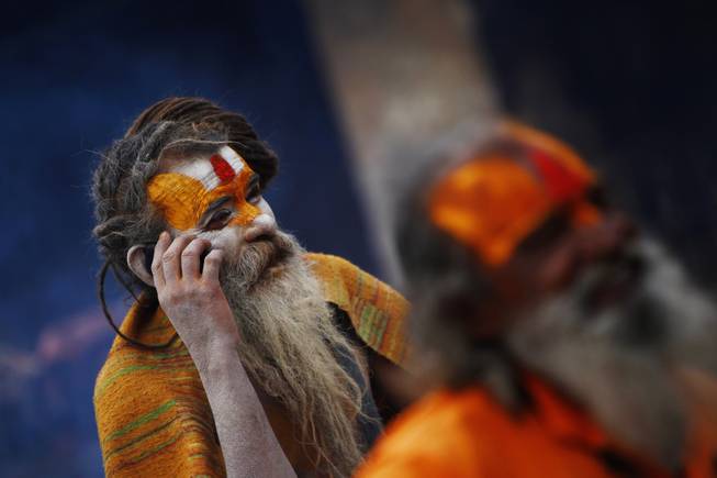 A Hindu holy man speaks on his cell phone in the courtyard of the Pashupatinath Temple in Katmandu, Nepal, Wednesday, Feb. 26, 2014. 