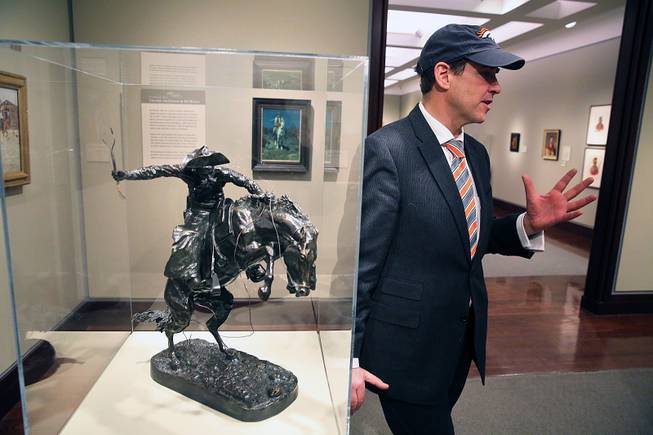 Denver Art Museum Director Christoph Heinrich speaks with a reporter as he leans against a Frederic Remington bronze statue of a cowboy riding a bucking horse, part of a collection on display inside the Denver Art Museum, Monday, Jan. 27, 2014. 