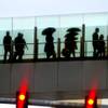 Some pedestrians carrying umbrellas, cross a foot bridge over Las Vegas Blvd. on Friday, Feb. 28, 2014.