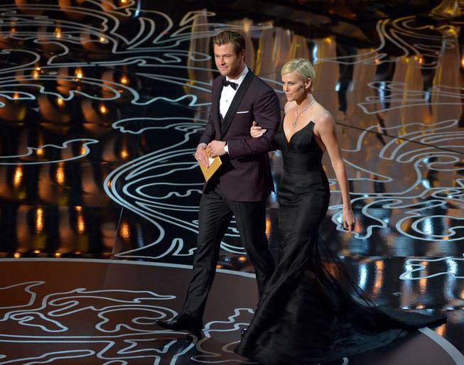 Chris Hemsworth, left, and Charlize Theron walk on stage during the Oscars at the Dolby Theatre on Sunday, March 2, 2014, in Los Angeles.  (Photo by John Shearer/Invision/AP)