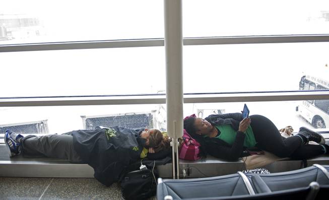 Hedwige Hattab, 29, Grenoble, France, left, and J'Que Ellis, 38, of Huntsville, Ala. wait  for flights to resume at Washington's Ronald Reagan National Airport, Monday, March 3, 2014. 