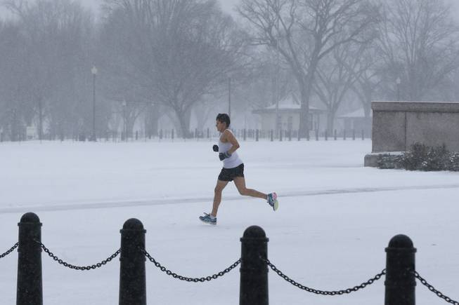 An unidentified man braves the elements as he runs on the National Mall as snow falls in Washington, Monday, March 3, 2014. 