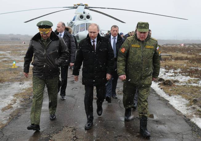 Russian President Vladimir Putin, center, and Defense Minister Sergei Shoigu, left, and the commander of the Western Military District Anatoly Sidorov, right, walk upon arrival to watch military exercise near St. Petersburg, Russia, Monday, March 3, 2014.