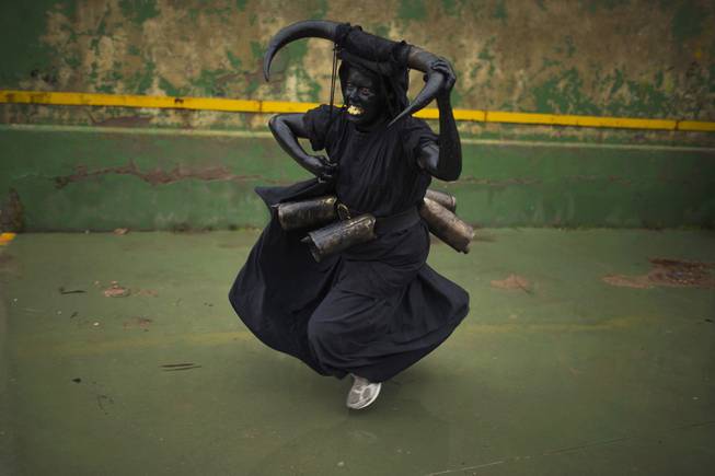 A woman, covered in oil and soot carrying bull horns on his head and cowbells on a belt representing the devil, runs while participating in carnival celebrations in the small village of Luzon, Spain, Saturday, March 1, 2014. Preserved records from the 14th century document Luzon's carnival, but the real origin of the tradition could be much older. Carnival festivals are celebrated in their own way around hundreds of villages in Spain. 