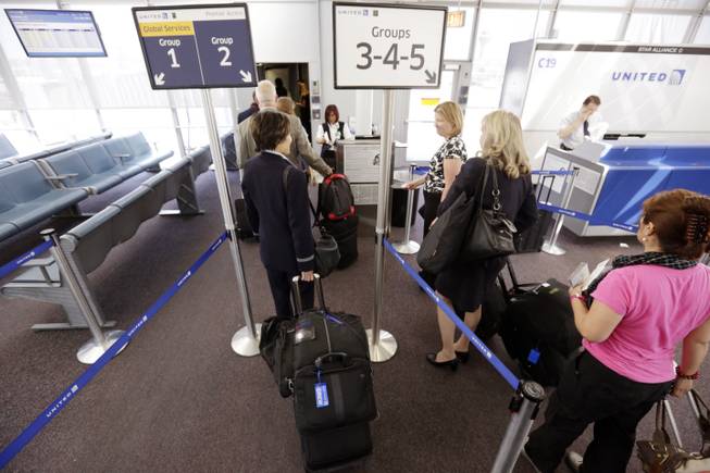In this May 8, 2013, file photo, groups of passengers wait at a United Airlines gate to board a flight in separate numbered lanes at O'Hare International Airport in Chicago. United has installed new bag sizers at airports and emailed its frequent fliers, reminding them of their carry-on size rules.