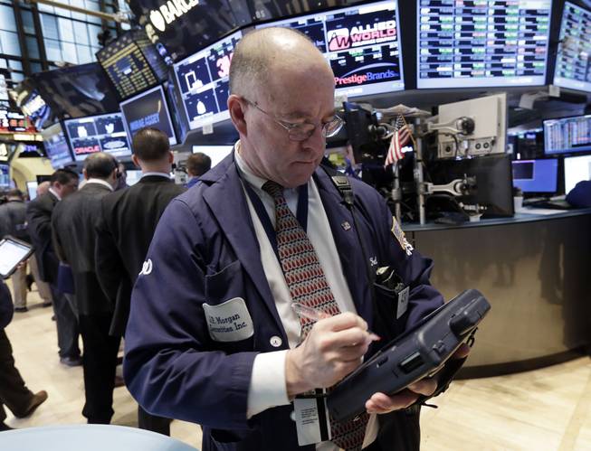 Trader Frederick Reimer uses his handheld device as he works on the floor of the New York Stock Exchange, Tuesday, March 4, 2014.