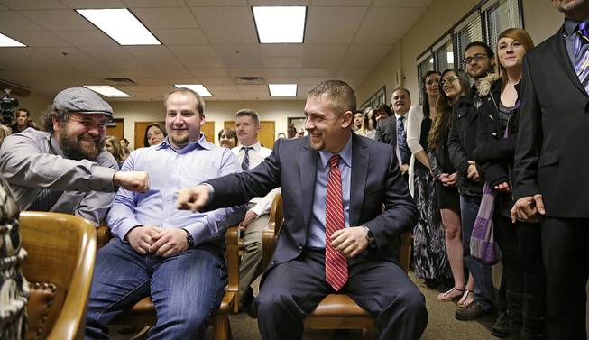 Sean Green, seated right, is congratulated by Sean Fitzgerald, left, as Scott O'neil looks on before Green is issued his new Washington state legal marijuana license Wednesday, March 5, 2014, in Olympia, Wash.