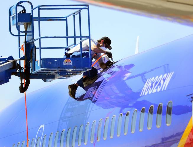 This April 3, 2011, file photo shows a member of the National Transportation Safety Board investigating the emergency landing of Southwest Airlines flight 812 by cutting away a portion of the plane's fuselage in Yuma, Ariz.