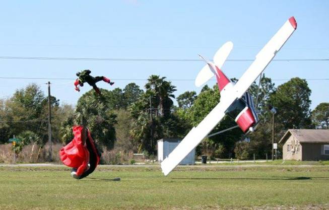 This photo released by the Polk County Sheriff's Office shows a plane nose-diving into the ground after getting tangled with a parachutist, left, Saturday, March 8, 2014, at the South Lakeland Airport in Mulberry, Fla. Both the pilot and jumper were hospitalized with minor injuries.