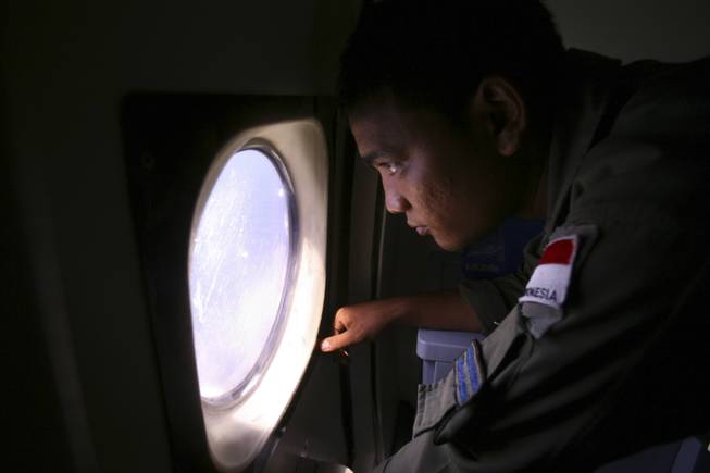 An Indonesian navy crew member scans the water bordering Indonesia, Malaysia and Thailand during a search operation for the missing Malaysian Airlines Boeing 777 near the Malacca straits on Monday, March 10, 2014.