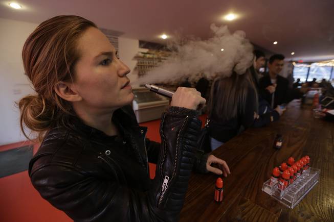 In this Feb. 20, 2014, photo, Talia Eisenberg, co-founder of the Henley Vaporium, uses her vaping device in New York.