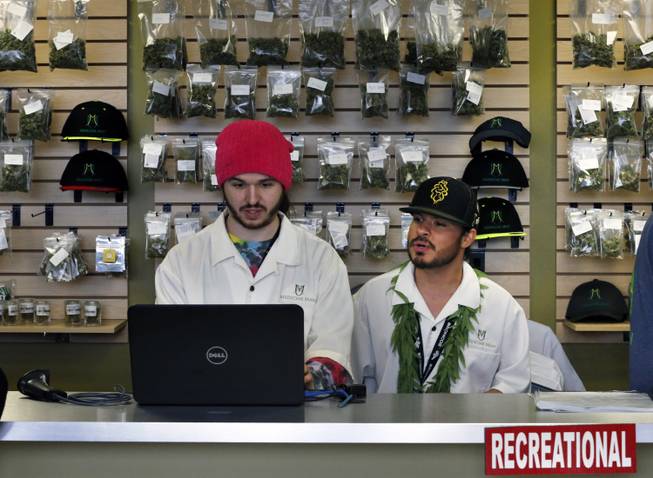 In this Jan. 1, 2014, file photo, employees Chris Broussard, left, and David Marlow, work behind sales counter inside Medicine Man marijuana retail store, which opened as a legal recreational retail outlet in Denver. Colorado made roughly $2 million in marijuana taxes in January, state revenue officials reported Monday, March 10, 2014, in the world's first accounting of the recreational pot business.