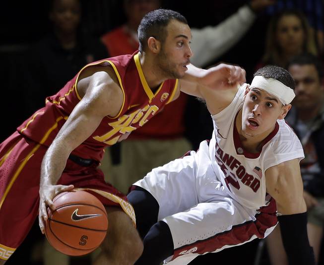 Southern California guard Julian Jacobs, left, dribbles next to Stanford forward Dwight Powell during the second half of an NCAA college basketball game on Thursday, Feb. 20, 2014, in Stanford, Calif. 