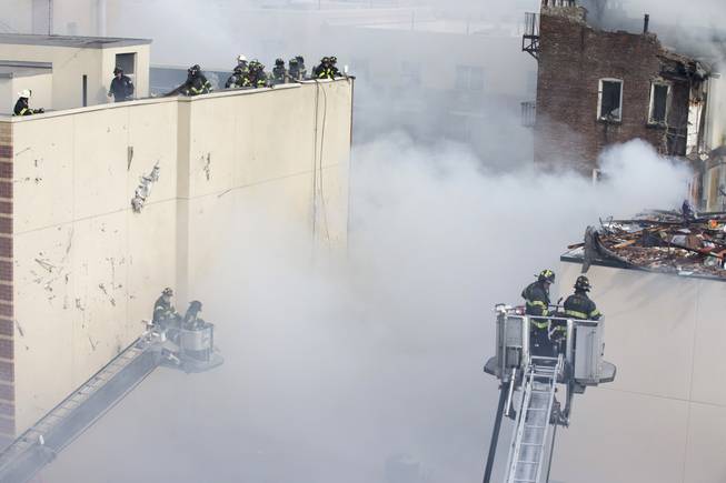Firefighters respond to a fire after an explosion and building collapse in the East Harlem neighborhood of New York, Wednesday, March 12, 2014. The explosion leveled an apartment building, and sent flames and billowing black smoke above the skyline.