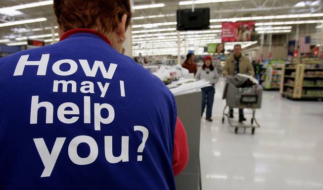 Customers at Wal-Mart head to the checkout lines past a worker with the company’s motto on the back of her vest on Nov. 13, 2005, in Salt Lake City.