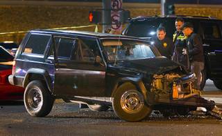 Metro Police investigators look over a vehicle after a shooting victim was involved in an accident at the 1-215 eastbound off-ramp at Eastern Avenue Thursday, March 13, 2014. The driver, who had been shot multiple times, may have been shot at another location, police said.