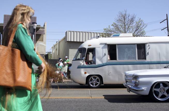A woman walks past as the antique vehicles from the High Roller Las Vegas club drive by during the annual St. Patrick's Day parade in Henderson Saturday, March 15, 2014.