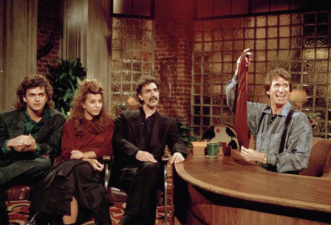 In this Sept. 24, 1986, file photo, comedian David Brenner hosts avant garde fusion musician Frank Zappa, center, and his children, Dweezil, left, and Moon Unit, during a taping of Brenner's "Nightlife" talk show in New York. Brenner holds a necktie given to Frank Zappa upon entering a restaurant earlier in the day. Brenner has died at the age of 78. 
