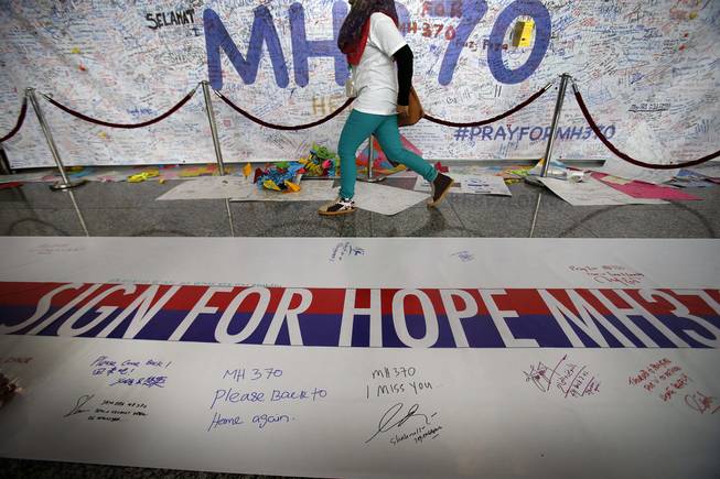 A woman walks past a banner filled with signatures and well-wishes for all involved with the missing Malaysia Airlines jetliner MH370 at the Kuala Lumpur International Airport, Sunday, March 16, 2014 in Sepang, Malaysia. Malaysian authorities Sunday were investigating the pilots of the missing jetliner after it was established that whoever flew off with the Boeing 777 had intimate knowledge of the cockpit and knew how to avoid detection when navigating around Asia.