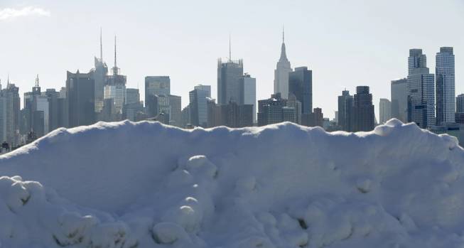 Piles of snow line the waterfront overlooking the New York City skyline in Weehawken, N.J., Friday, Feb. 14, 2014. Commuters faced slick roads on Friday after yet another winter storm brought snow and ice to the East Coast, leaving at least 24 people dead.