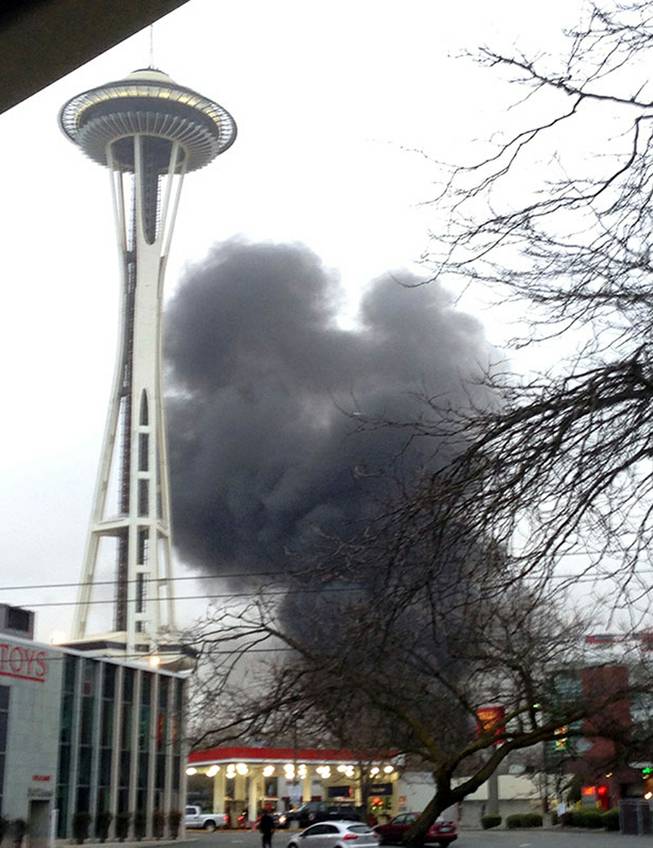 In this photo provided by KIRO- TV, smoke rises at the scene of a helicopter crash outside the KOMO-TV studios near the space needle in Seattle on Tuesday, March 18, 2014.