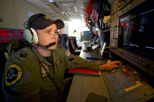 In this Wednesday, March 19, 2014, photo released by the Australia Defense Department, Royal Australian Air Force airborne electronics analyst Flight Sgt. Tom Stewart, on board an AP-3C Orion, watches a radar screen over the Southern Indian Ocean during a search operation for missing Malaysia Airlines flight MH370.