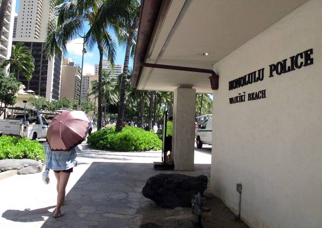A pedestrian walks in front of a Honolulu Police Department station in Honolulu's tourist area of Waikiki on Wednesday, March 19, 2014. 