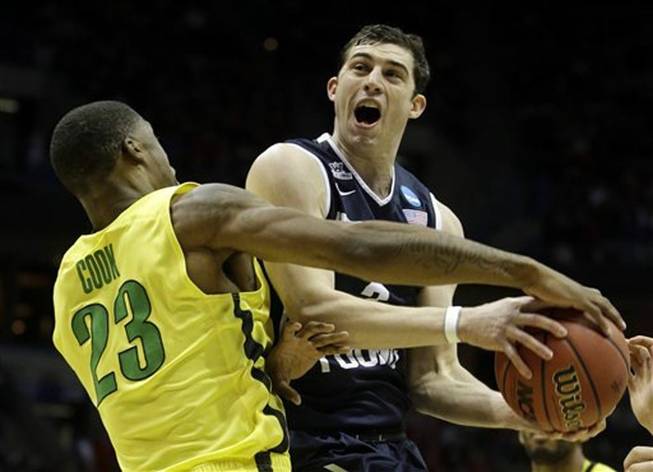 BYU guard Matt Carlino is fouled by Oregon forward Elgin Cook (23) during the first half of a second-round game in the NCAA college basketball tournament Thursday, March 20, 2014, in Milwaukee.