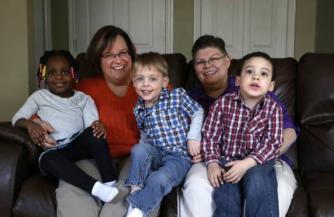 In this March 5, 2013, file photo, April DeBoer, second from left, sits with her adopted daughter Ryanne, 3, left, and Jayne Rowse, fourth from left, and her adopted sons Jacob, 3, middle, and Nolan, 4, right, at their home in Hazel Park, Mich. A federal judge has struck down Michigan's ban on gay marriage, Friday, March 21, 2014, the latest in a series of decisions overturning similar laws across the U.S. The two nurses who've been partners for eight years claimed the ban violated their rights under the U.S. Constitution.