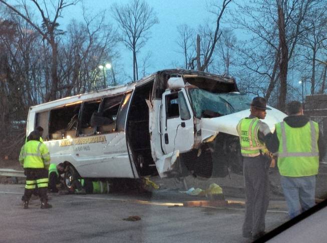 Police investigate the scene of a bus accident on Interstate 95 early Sunday, March 23, 2014, in Fairfax County, Va. The shuttle bus struck a guardrail and overturned before dawn Sunday just south of the nation's capital, leaving at least one person dead and sending 16 others to the hospital, Virginia State Police said.