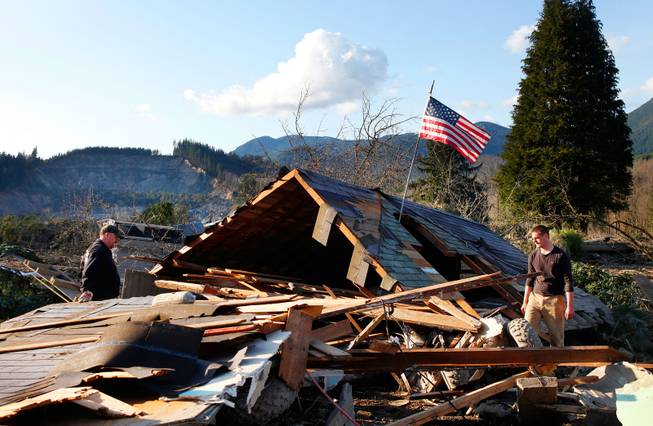 Brian Anderson, left,  and Coby Young search through the wreckage of a home belonging to the Kuntz family Sunday, March 23, 2014, near Oso, Wash. 