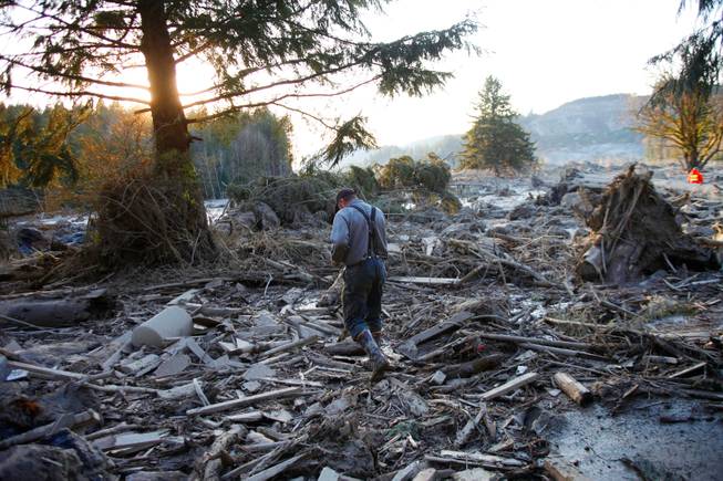 Steve Skaglund walks across the rubble on the east side of Saturday's fatal mudslide near Oso, Wash., Sunday, March 23, 2014. 