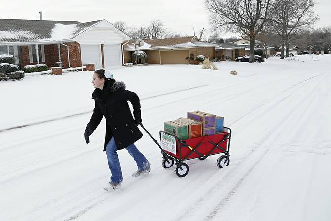 Girl Scout Katie Francis pulls her wagon full of boxes of cookies in the snow through a neighborhood in Warr Acres selling cookies in Oklahoma City, Feb. 6, 2014.