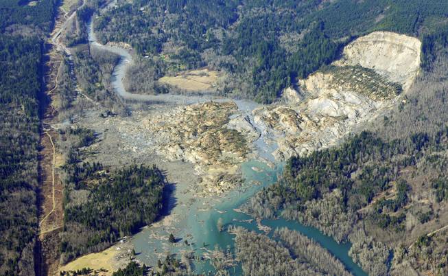 The massive mudslide that killed at least eight people and left dozens missing is shown in this aerial photo, Monday, March 24, 2014, near Arlington, Wash. The search for survivors grew Monday, raising fears that the death toll could climb far beyond the eight confirmed fatalities. (AP Photo/Ted S. Warren)